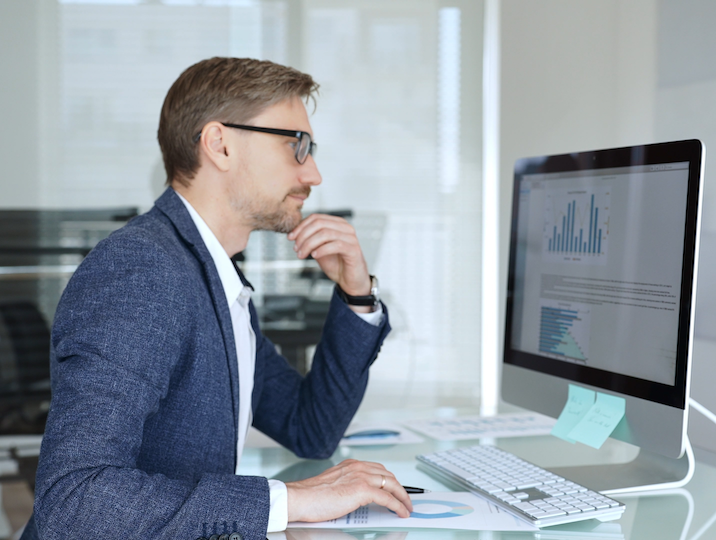 Businessman in a blue jacket analyzing financial data on computer