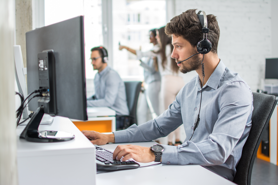 Young customer success support operator with hands-free set working at desk