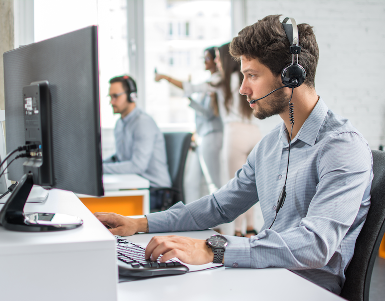 Young customer success support operator with hands-free set working at desk